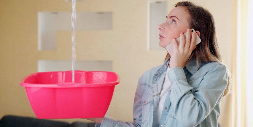 woman holding a bucket catching leaky roof